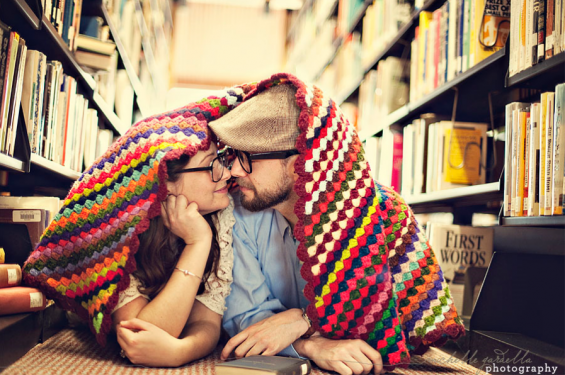 couple snuggling under blanket in the library library engagement shoot with blanket