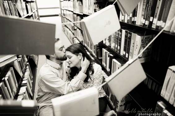 couple embracing behind books library book engagement shoot